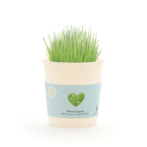 Tasse avec de l’herbe verte et une banderole représentant un cœur vert et le texte « On ne peut pas tondre un cœur qui court ».