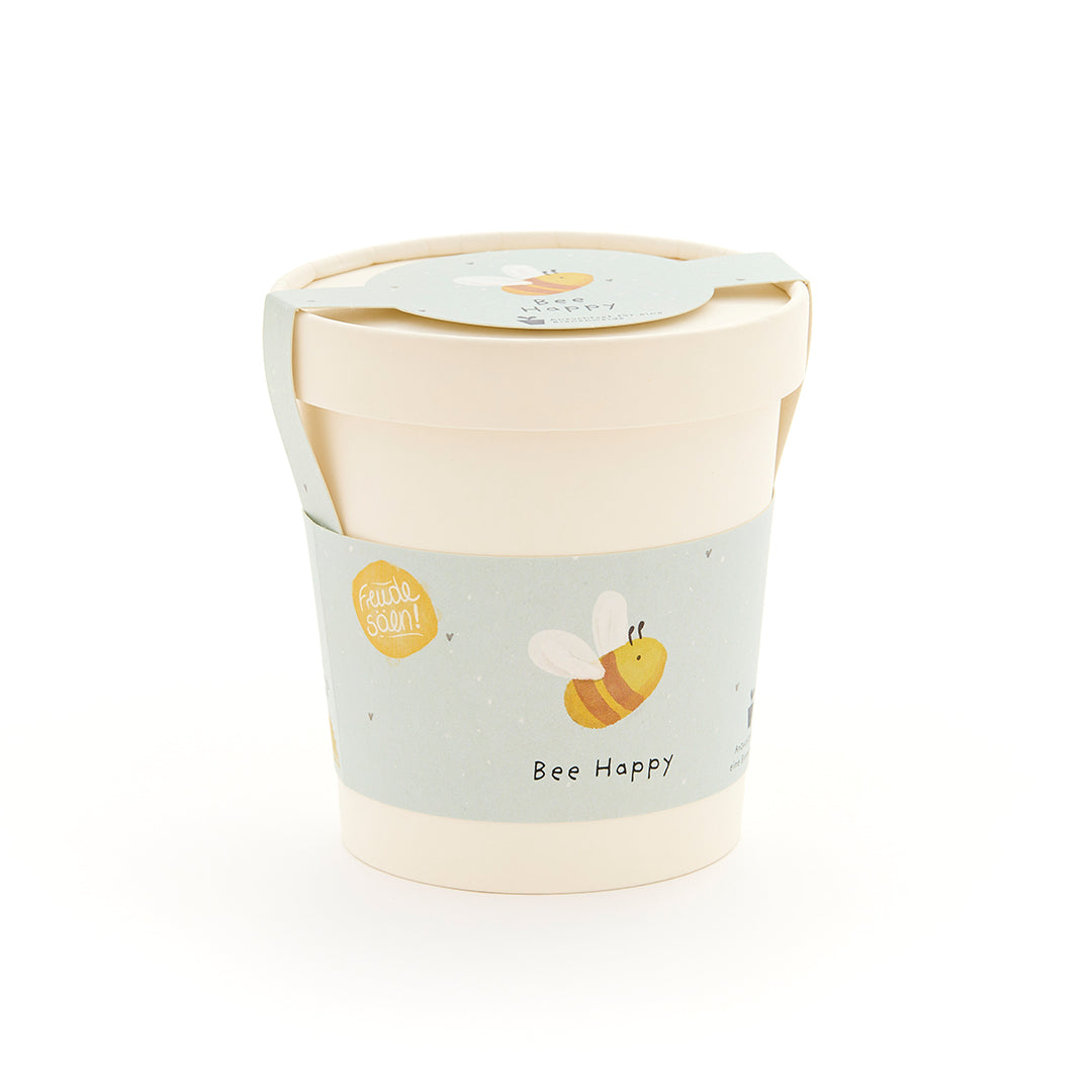 Mug beige avec une étiquette bleu clair représentant une abeille dessinée et les mots « Bee Happy ».