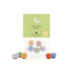 Sachet contenant des boules de graines colorées et une étiquette verte comportant un dessin d'oie et le texte « Merci beaucoup pour l'oie - graines de fleurs sauvages ».