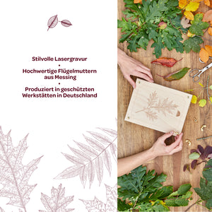 Deux mains tiennent une plaque de bois avec une délicate gravure laser d'une feuille, entourée de diverses feuilles d'automne colorées et de matériaux d'artisanat ; à côté se trouve un texte avec des informations sur la gravure laser, les écrous à oreilles en laiton et la production en Allemagne.