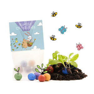 À côté se trouve un sac portant l'inscription « Salutations florales de Pâques », ainsi que des bombes de graines colorées, de jeunes plants, de la terre et des dessins d'abeilles et de papillons.