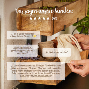 Une photo d'une jardinière en bois avec divers avis de clients en allemand, une main tenant un petit sac en tissu, des fleurs décoratives et des plantes en arrière-plan.