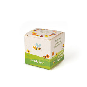 Petite boîte étiquetée « Seedbomb » entourée d'illustrations florales, avec des références au fait qu'elle est 100 % naturelle et respectueuse des abeilles.
