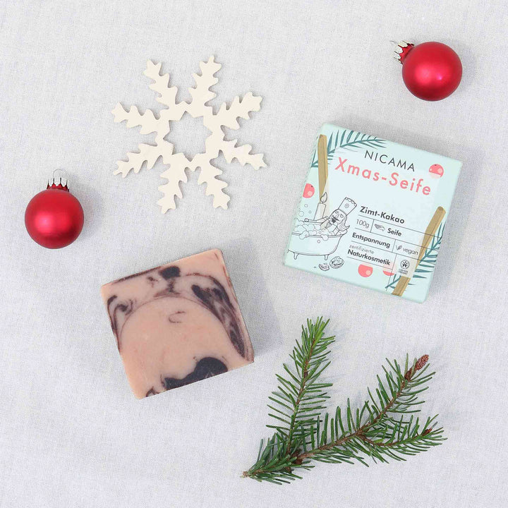 Composition de Noël avec savon, branche de sapin, décoration de flocon de neige et boules de Noël rouges sur fond clair