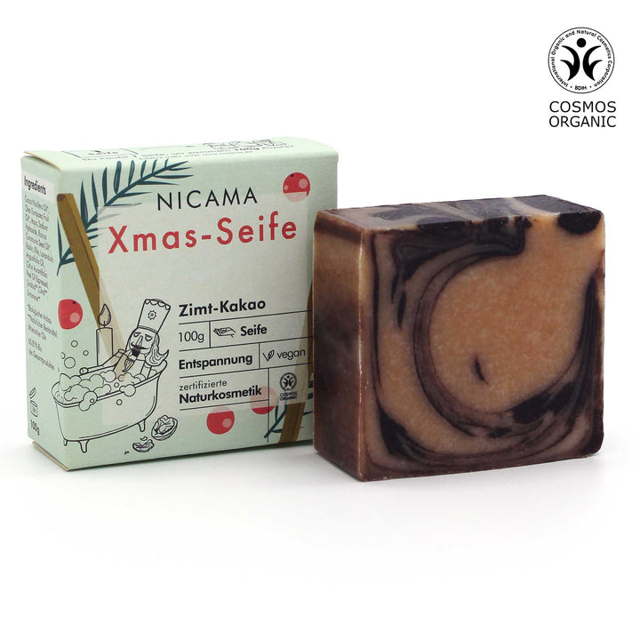 Savon de Noël NICAMA au parfum cannelle-cacao à côté de son emballage, cosmétique naturel certifié, 100g, vegan
