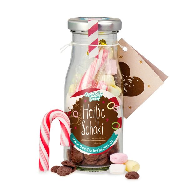 Bouteille de lait étiquetée « Chocolat chaud » et bonbons comme des guimauves, des biscuits au chocolat et des cannes de bonbon.