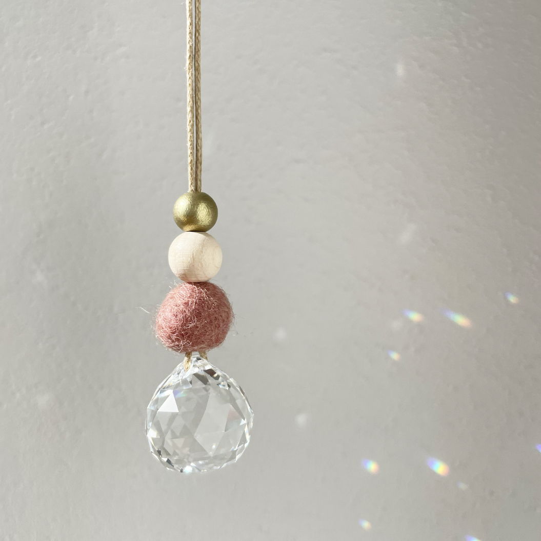 Pendentif avec cristal clair et perles colorées sur un fil sur un fond flou