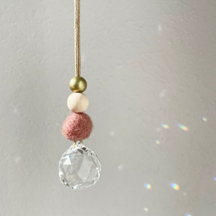Pendentif avec cristal clair et perles colorées sur un fil sur un fond flou