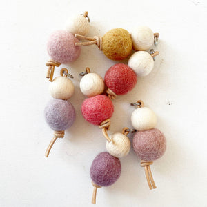 Boules de feutre colorées et perles en bois sur une ficelle.