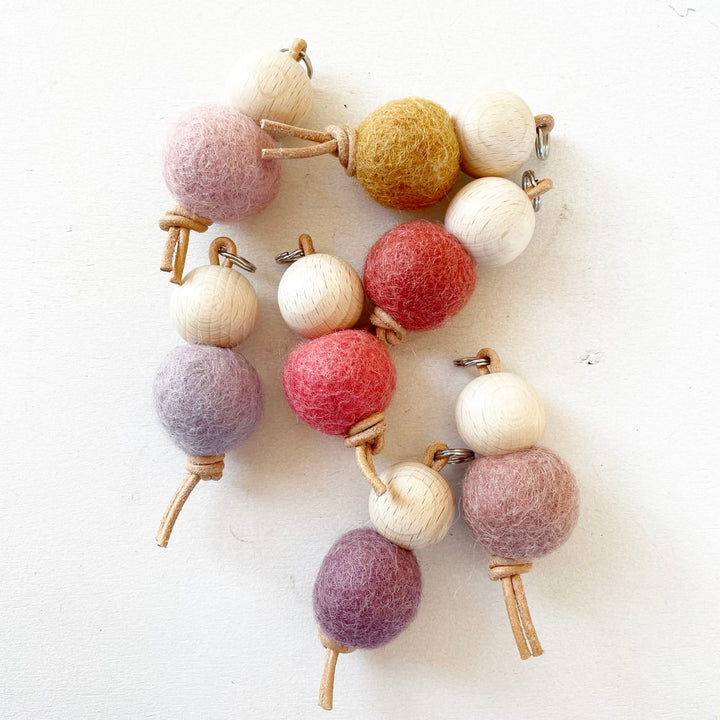 Boules de feutre colorées et perles en bois sur une ficelle.