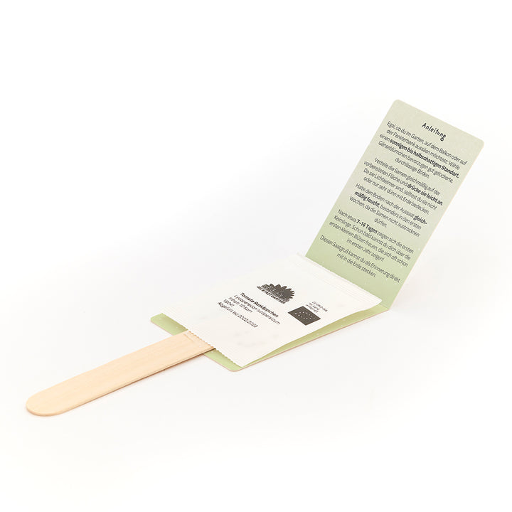 Bâtonnets en bois avec sachets de graines et instructions illustrées en allemand.