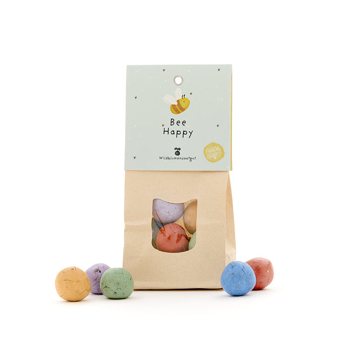 Sac en papier avec des bombes de graines colorées et une étiquette « Bee Happy » pour les fleurs sauvages.