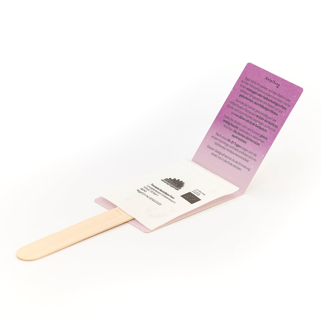 Un kit de plantation avec des bâtons en bois, des sachets de graines et des instructions dépliées sur du carton violet.