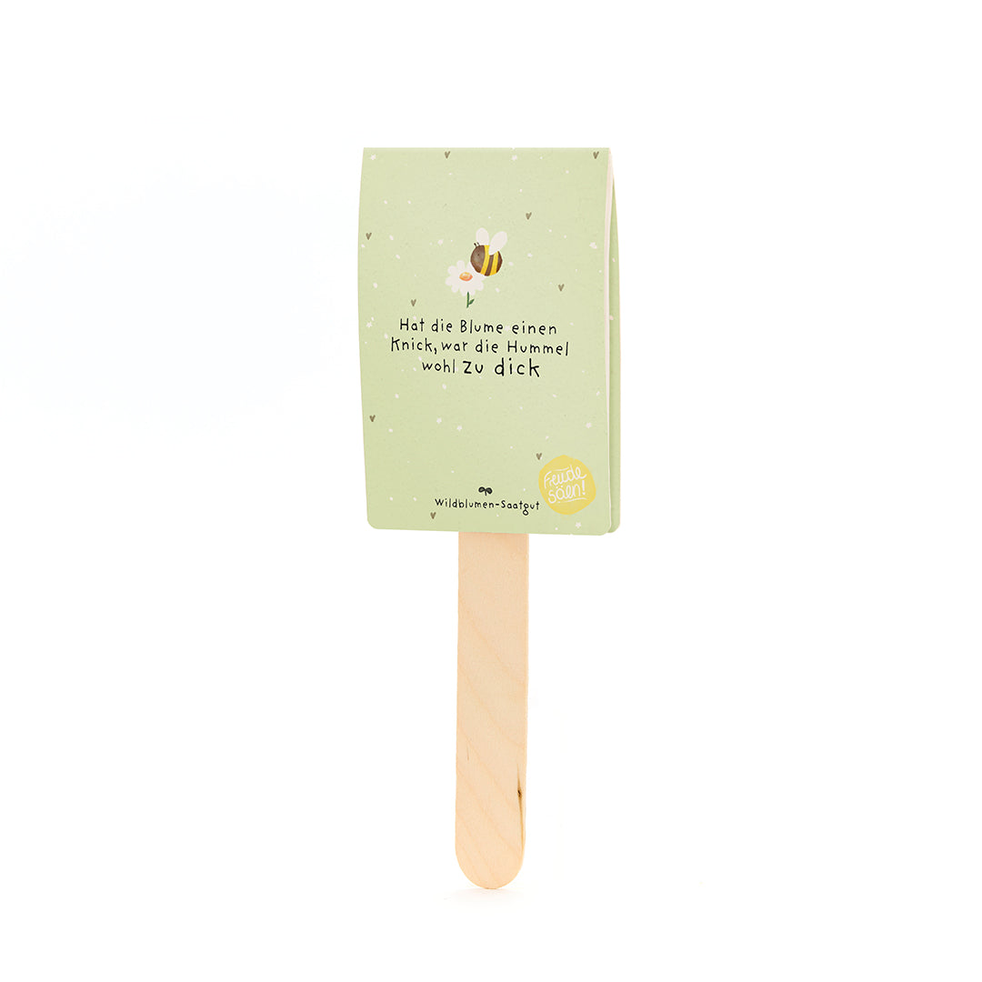 Étiquette en papier vert avec un motif d'abeille et l'inscription « Si la fleur a un pli, le bourdon était probablement trop gros » sur un bâton en bois.