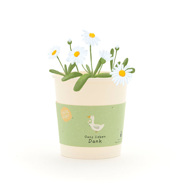 Un pot de fleurs de couleur crème avec des marguerites blanches et une étiquette verte, comportant un dessin d'une oie et le texte « Merci beaucoup, Oie ».