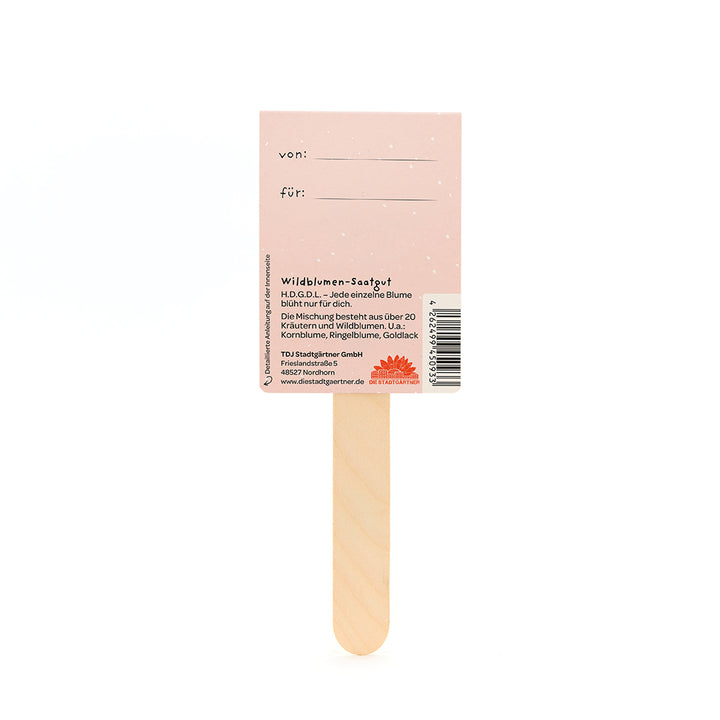 Tige avec carte rose sur laquelle est écrit « de : » et « pour : » et fournit des informations sur les graines de fleurs sauvages en allemand.