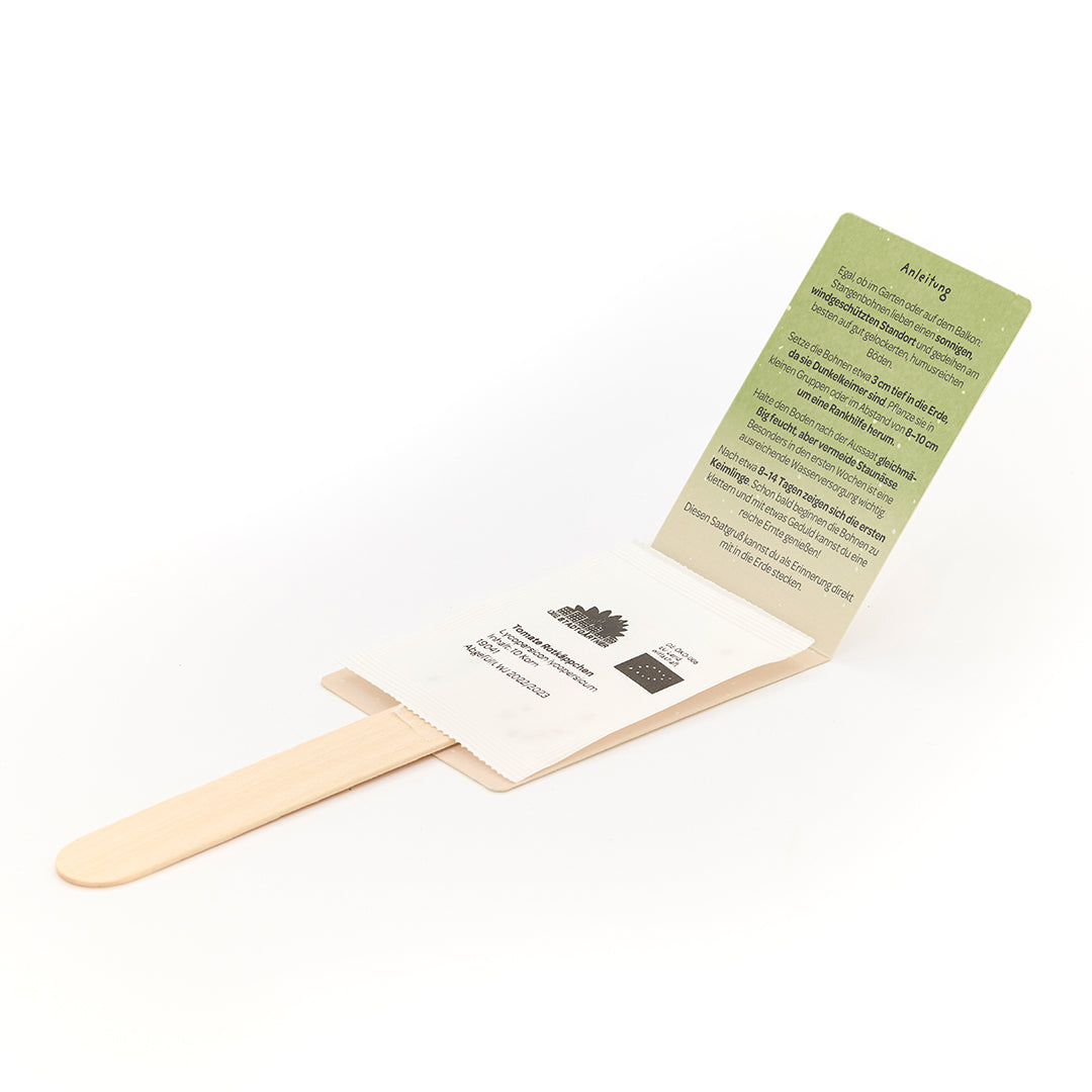 Bâton en bois avec une enveloppe contenant une carte d'instructions verte et un sachet de graines.