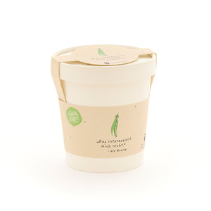 Une tasse blanche avec une étiquette beige représentant un petit pois vert et la phrase « Je m'en fiche. – le haricot. »