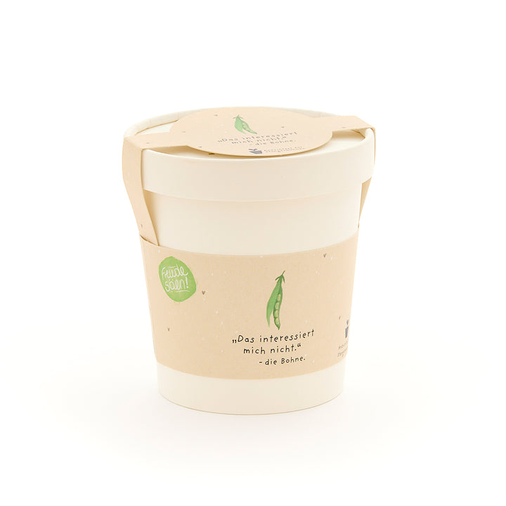 Une tasse blanche avec une étiquette beige représentant un petit pois vert et la phrase « Je m'en fiche. – le haricot. »
