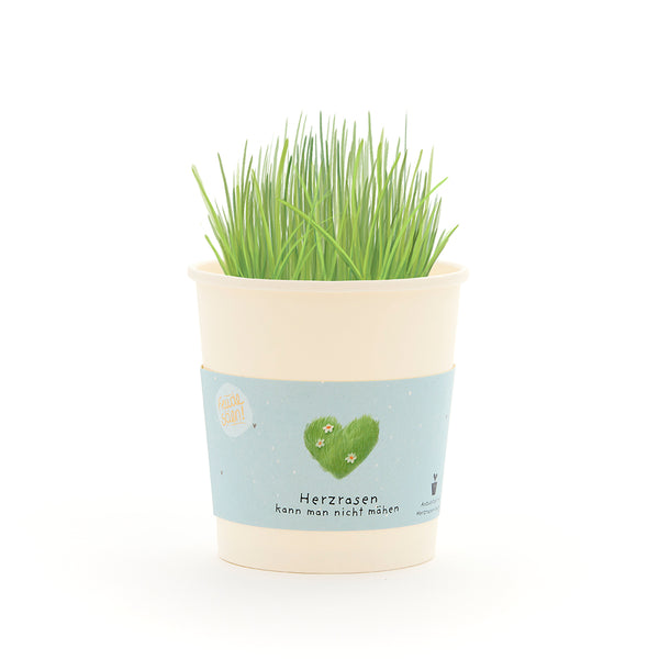 Tasse avec de l’herbe verte et une banderole représentant un cœur vert et le texte « On ne peut pas tondre un cœur qui court ».