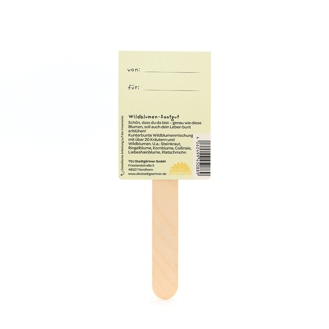Dos d'un bâtonnet de graines de fleurs sauvages en bois avec une étiquette jaune et une description en allemand.