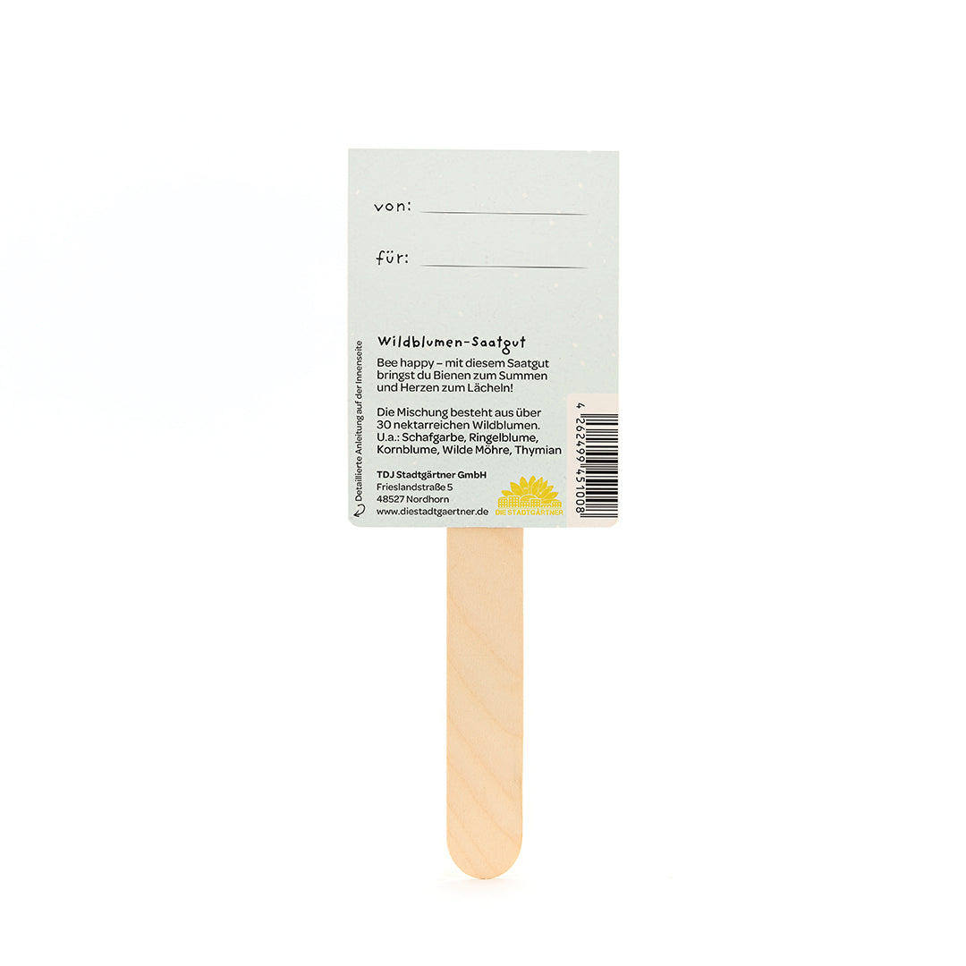 Dos d'un sachet de graines avec un bâtonnet en bois contenant des informations sur les graines de fleurs sauvages et un espace pour « de : » et « pour : ».