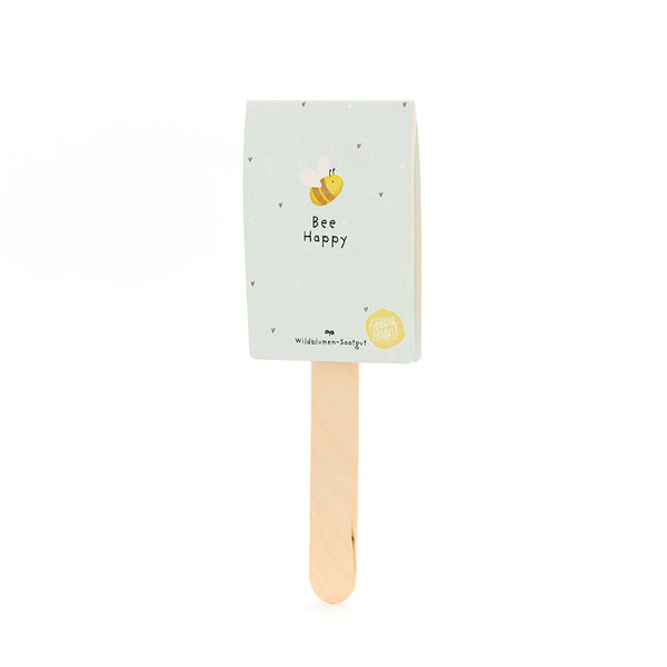Bâton en bois avec une étiquette bleu clair comportant un dessin d'abeille et le texte "Bee Happy" ; graines de fleurs sauvages.