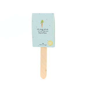 Un bâton en bois avec une étiquette bleu clair, un dessin de carotte et le texte « Je t'aime avec toutes tes carottes ».