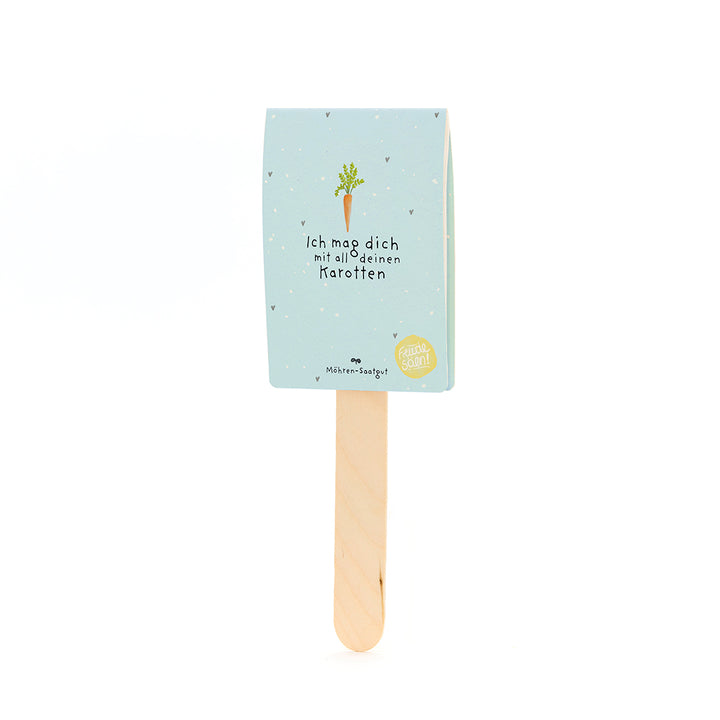 Un bâton en bois avec une étiquette bleu clair, un dessin de carotte et le texte « Je t'aime avec toutes tes carottes ».