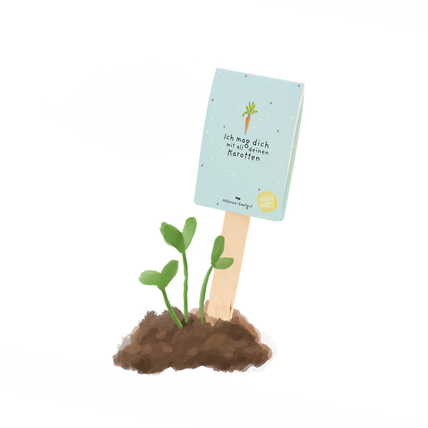 Une petite plante verte pousse dans le sol, avec un panneau à côté sur lequel on peut lire : « Je t'aime avec toutes tes carottes. »