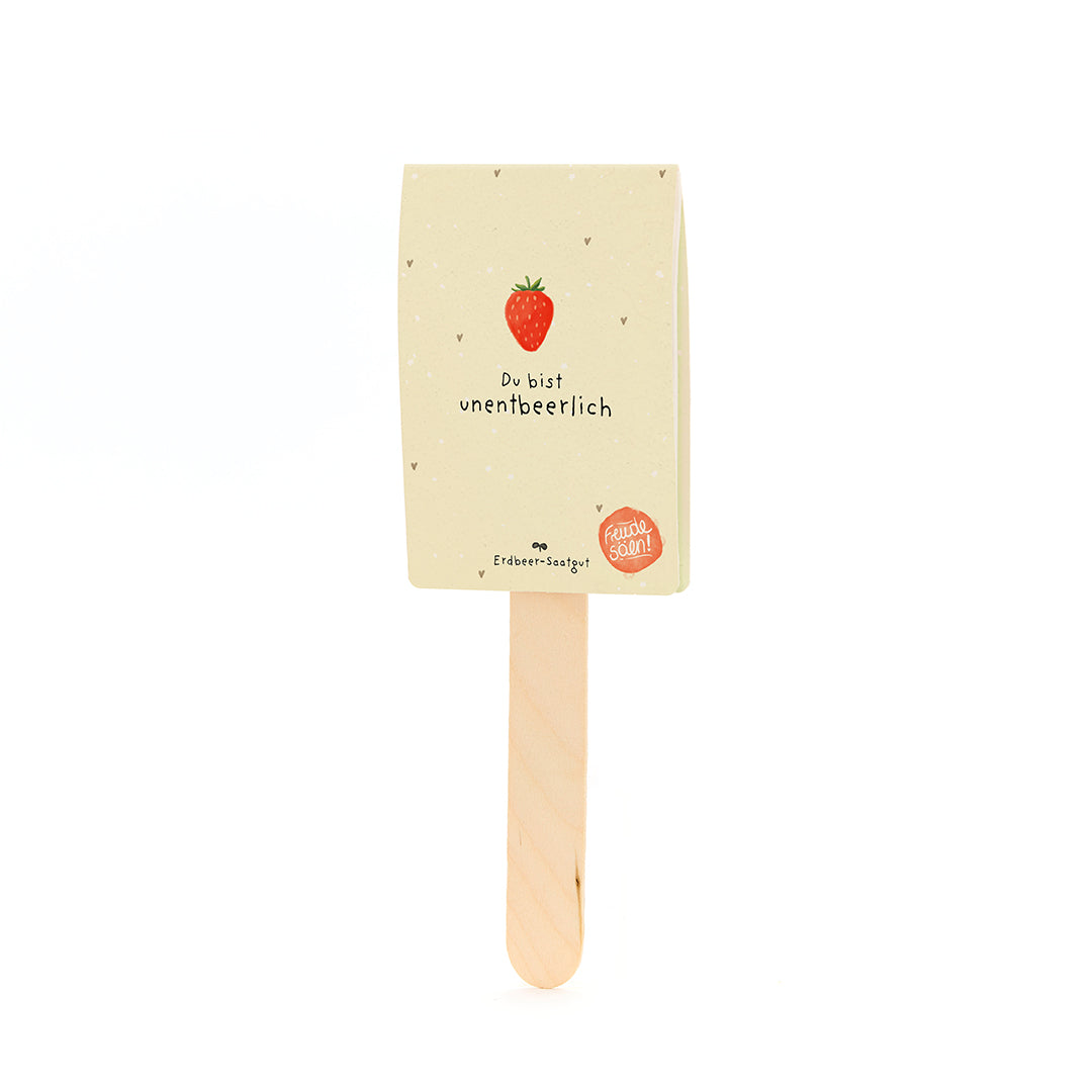 Bâton en bois avec une étiquette représentant une fraise et le texte « Tu es indispensable » et « Graines de fraise ».