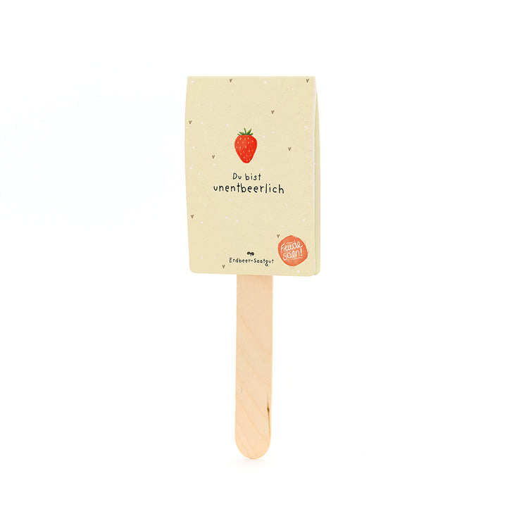 Bâton en bois avec une étiquette représentant une fraise et le texte « Tu es indispensable » et « Graines de fraise ».