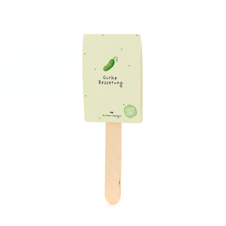 Un bâton en bois avec une étiquette en papier beige-vert représentant un concombre dessiné et le texte « Amélioration du concombre ».