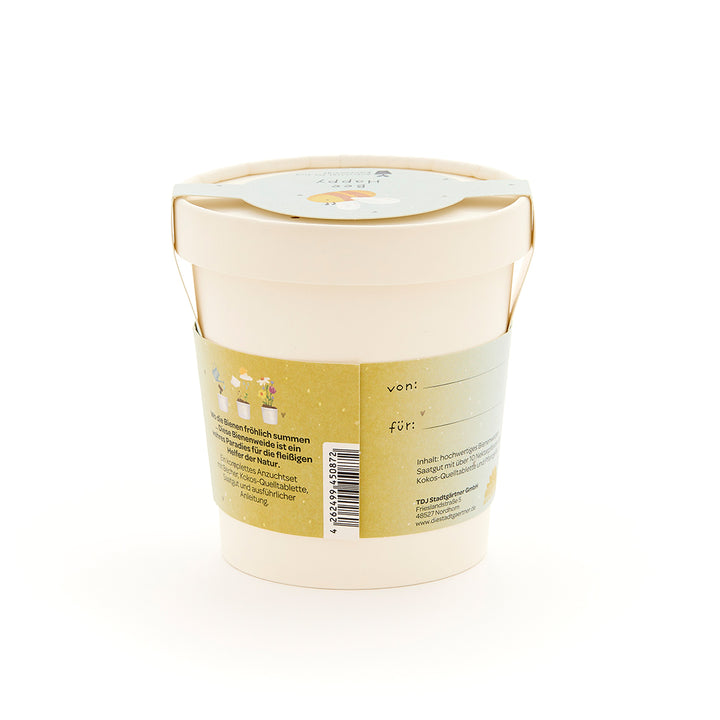Pot de fleurs beige avec une étiquette verte comportant du texte et de petites illustrations de fleurs et d'abeilles.