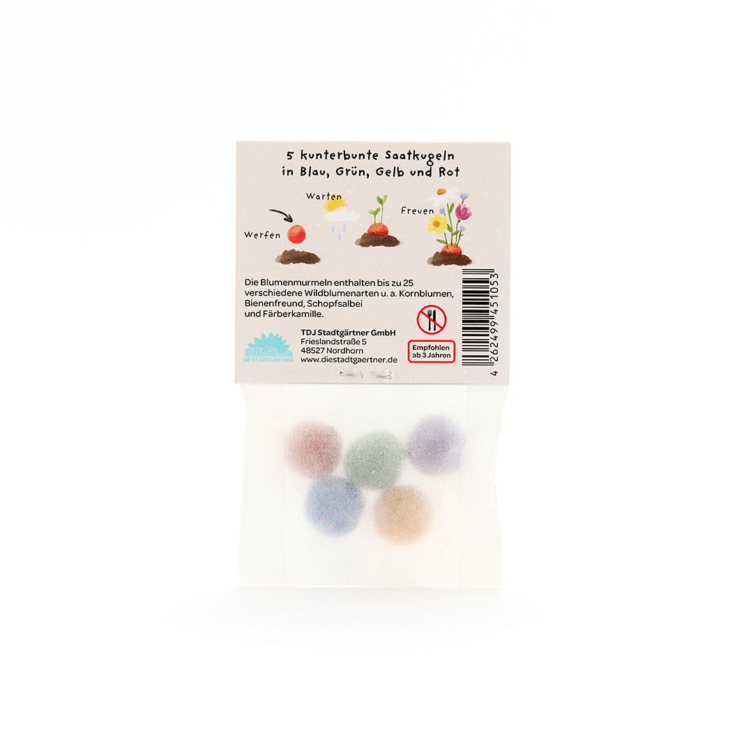 Cinq boules de graines colorées dans un emballage transparent avec des instructions étiquetées en allemand.