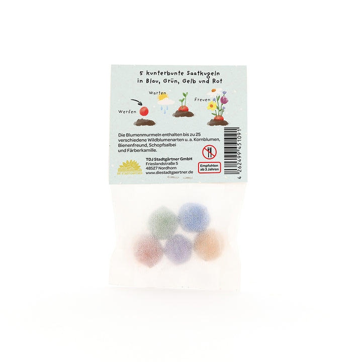 Cinq boules de graines colorées dans un emballage transparent, avec instructions et illustrations en allemand sur l'étiquette.
