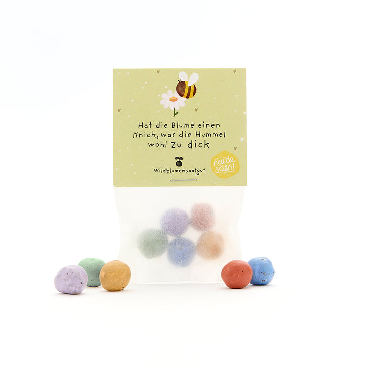 Sachet contenant des boules de graines colorées et une étiquette avec un dessin d'abeille et le dicton « Si la fleur est courbée, le bourdon était probablement trop gros ».