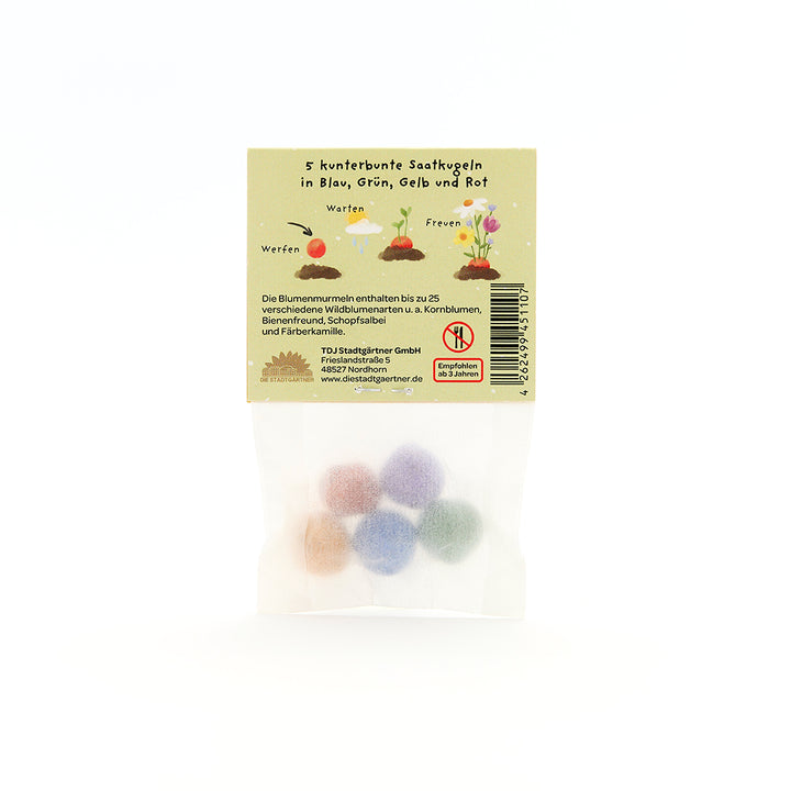 Cinq boules de graines colorées dans un sac transparent avec emballage beige et instructions en allemand pour les fleurs sauvages.