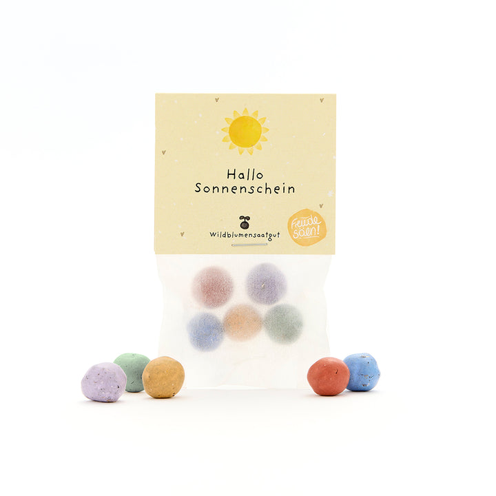Sachet avec boules de graines colorées et une étiquette "Hello Sunshine", ainsi qu'un soleil et des petits coeurs, des graines de fleurs sauvages.