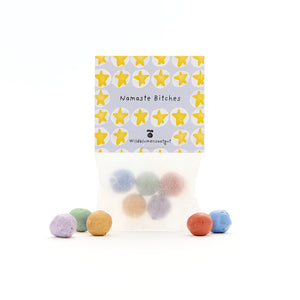 Sachet de boules de graines colorées, étiquette avec des étoiles jaunes et les mots « Namaste Bitches » et « Wildflower Seeds ».