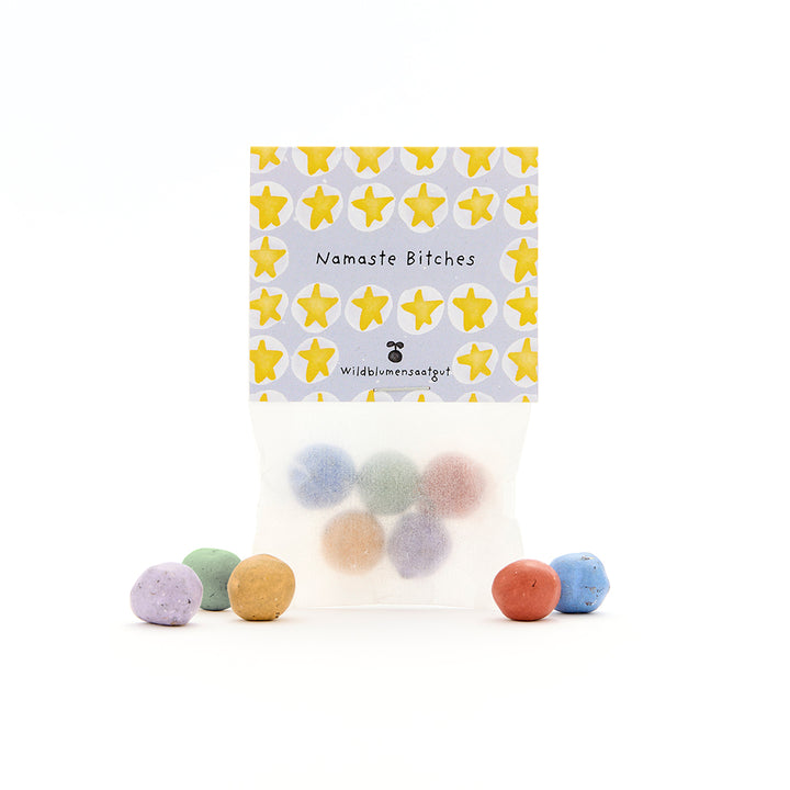Sachet de boules de graines colorées, étiquette avec des étoiles jaunes et les mots « Namaste Bitches » et « Wildflower Seeds ».