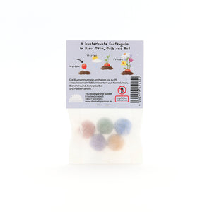 Cinq boules de graines colorées en bleu, vert, jaune et rouge dans un emballage avec description et instructions en allemand.