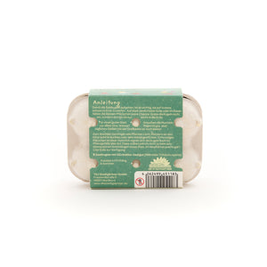 Un petit paquet avec des instructions et un code-barres, probablement pour des graines, sur fond blanc.