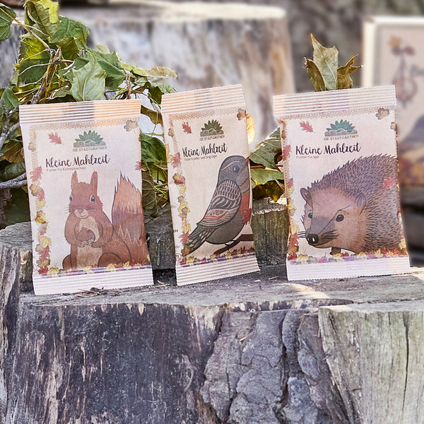 Trois emballages de nourriture pour animaux de compagnie avec des images d'un écureuil, d'un oiseau et d'un hérisson sur des troncs d'arbres"