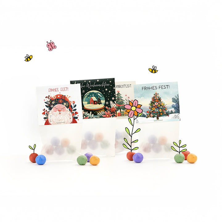 Trois sacs-cadeaux sur le thème de Noël avec des boules colorées, des motifs de Noël illustrés et les mots « Joyeux Noël ! » ainsi que des fleurs dessinées, des abeilles et un papillon.
