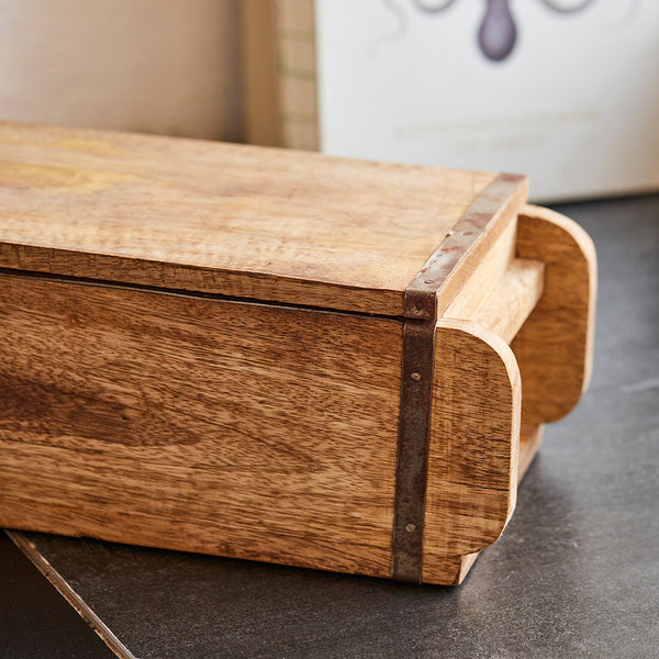 Boîte rectangulaire en bois avec renforts métalliques sur une surface foncée.