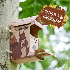 Borne d'alimentation en carton avec un motif d'écureuil fixée à un arbre, avec l'inscription « Buffet en plein air » et un panneau indiquant « Résistant aux intempéries et rechargeable ».
