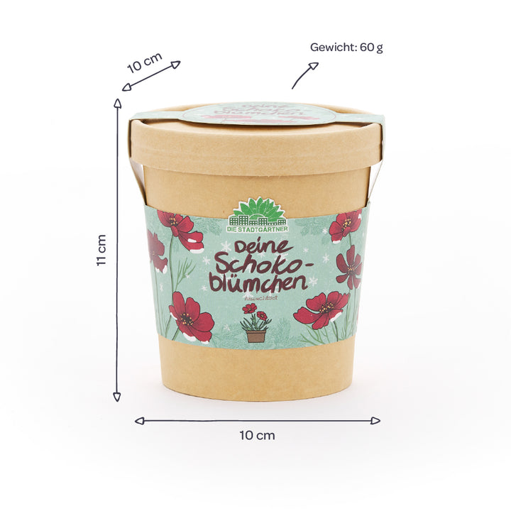 Gobelet en papier avec motif floral et inscription « Deine Schokoblümchen », à côté des dimensions (10 cm de diamètre, 11 cm de hauteur) et du poids (60 g) indiqués en allemand.