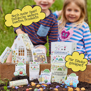 Deux enfants souriants avec des sacs de graines colorés dans le jardin, entourés de bulles de dialogue avec les mots « Encore plus amusant ! Découvrez nos produits colorés » et « Convient aux enfants ».