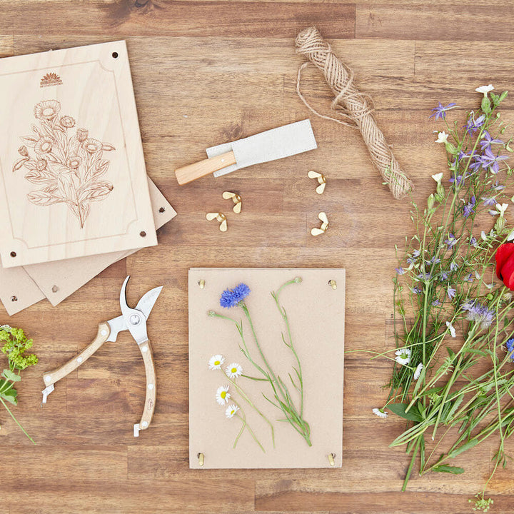Matériel d'artisanat et fleurs pressées sur une table en bois.